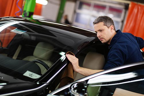 man in blue shirt polishing a black car