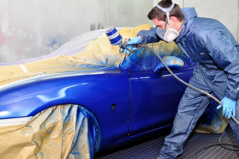 man dressed in protective gear repairing the aluminum on a car