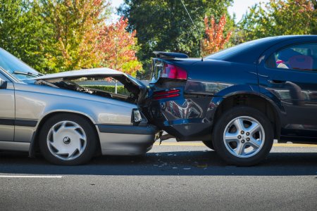 parked silver vehicle with busted hood that has collided into a parked blue vehicle's bumper